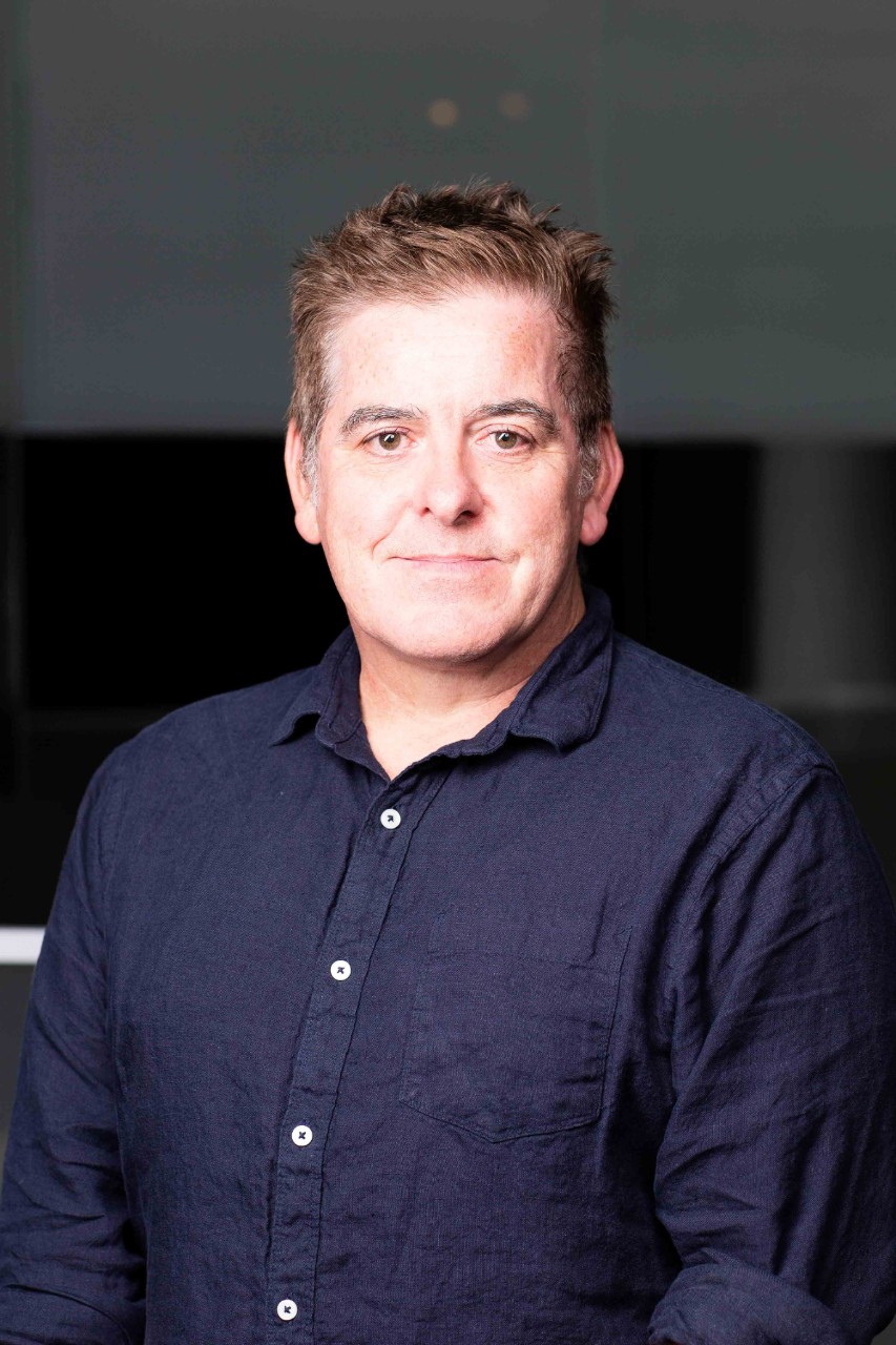 a man in a blue shirt smiling at the camera