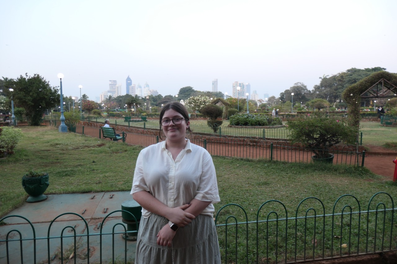 Imogen smiling at camera in front of a garden