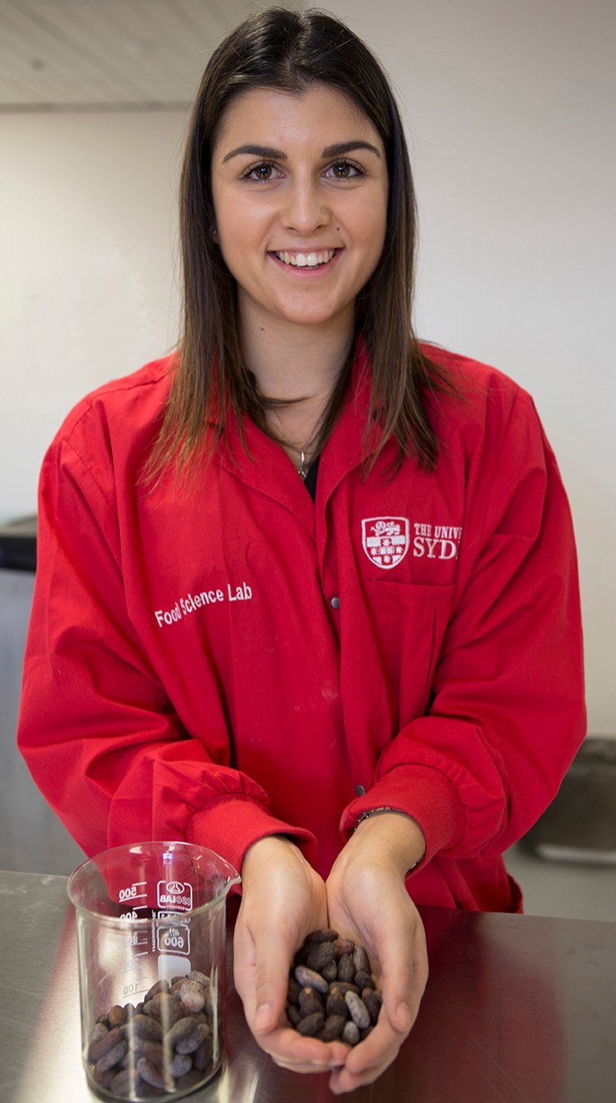 Katrina Carlino in the food science laboratory holding cocoa beans.