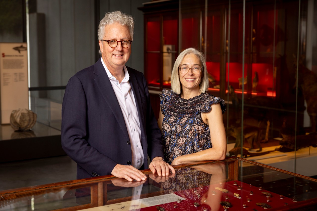 a man and a woman in a museum, stand together smiling at the camera