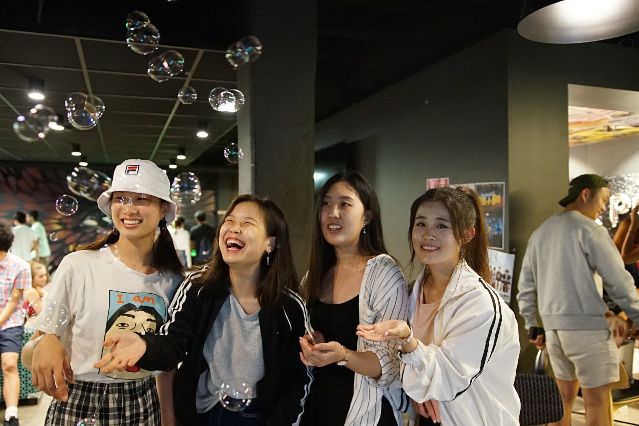 Four students laughing and socialising in the Queen Mary Building 