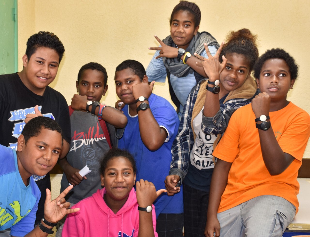 Group of Pacific children showing off digital trackers of their wrists