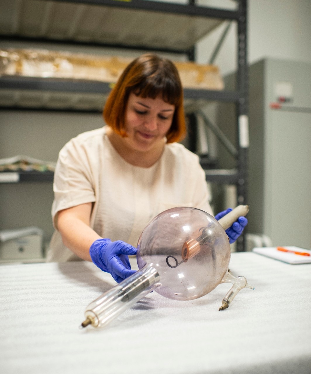 Sylvia wearing purple latex gloves and holding a spherical glass object. 