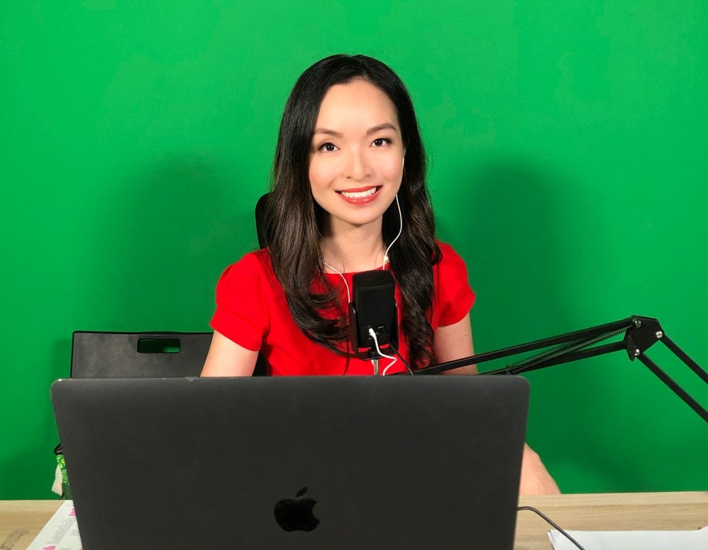 Victoria Ong moderating a conference against a green screen.