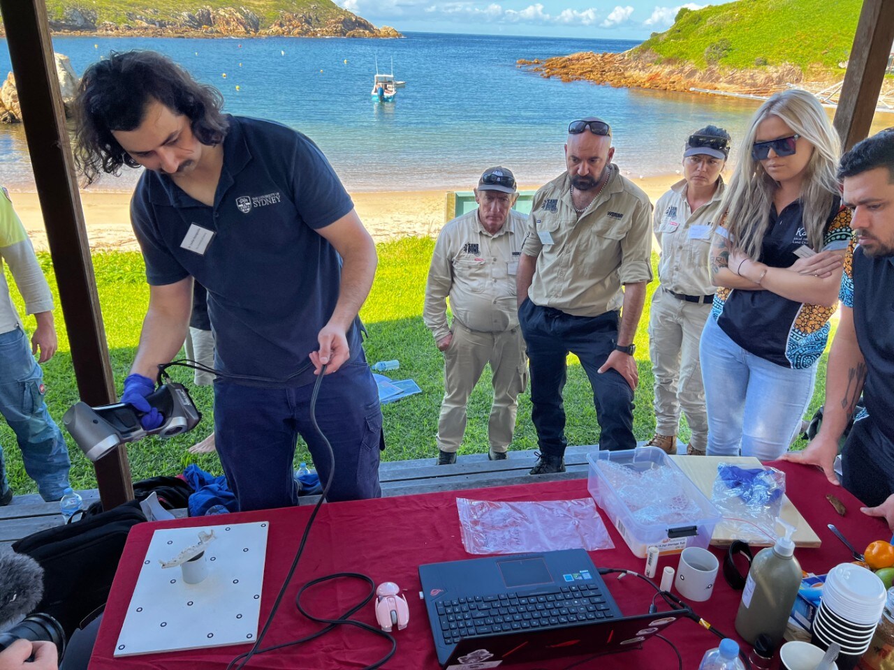 Dr Loukas Koungoulos (University of Sydney) completing a 3D scan of a dingo bone on Broughton Island with Worimi community representatives. 