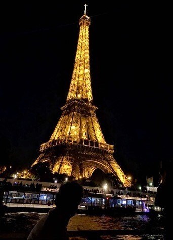 Aman in front of a lit-up Eiffel Tower