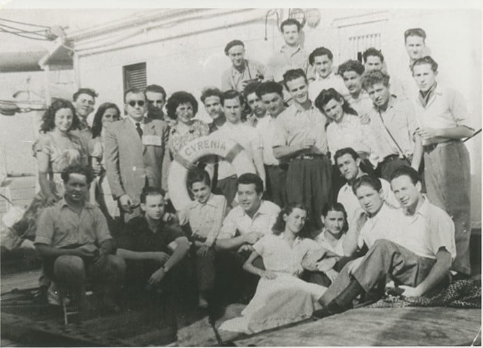 Old photograph of a group of Holocaust survivors on a ship named Cyrenia as inscribed on the ship's lifebouy float