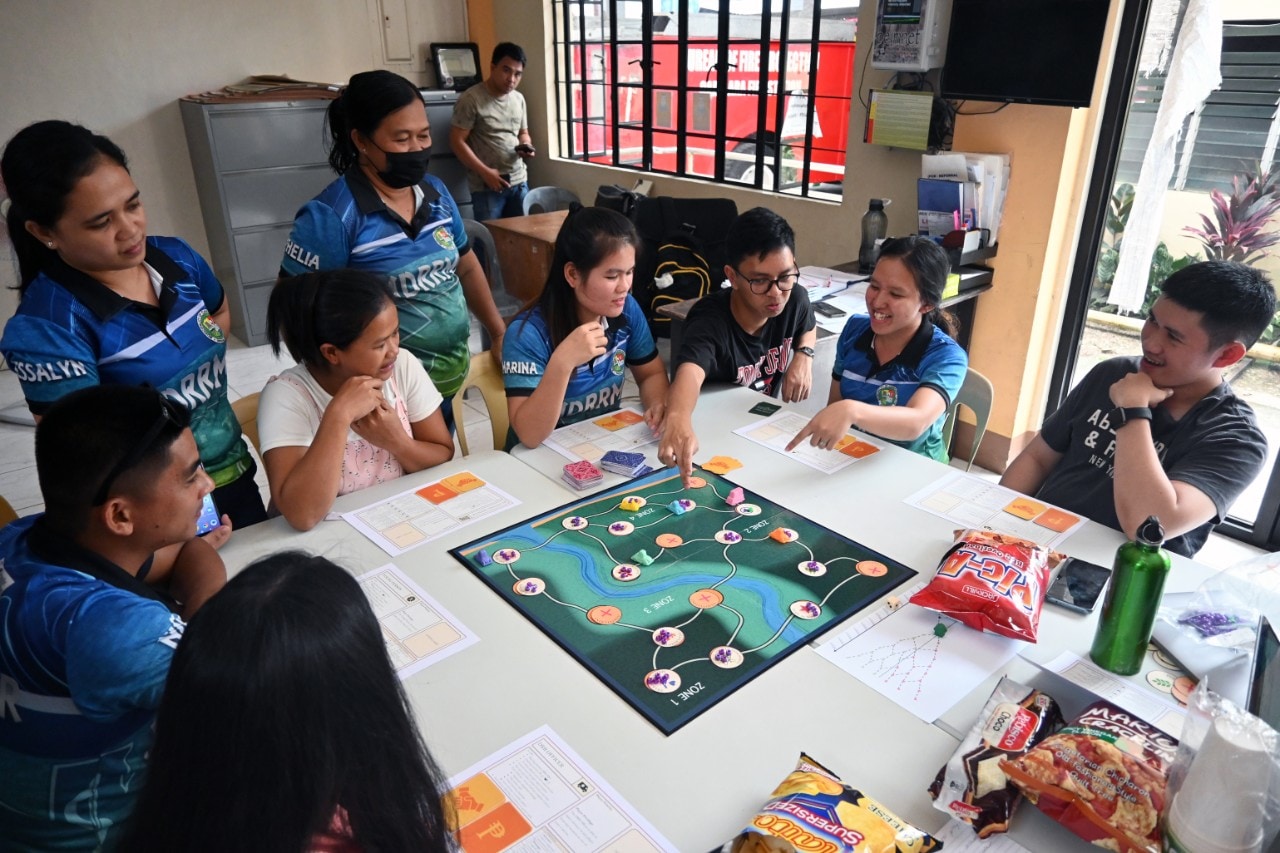 People gathered around interactive table top game in the Philippines