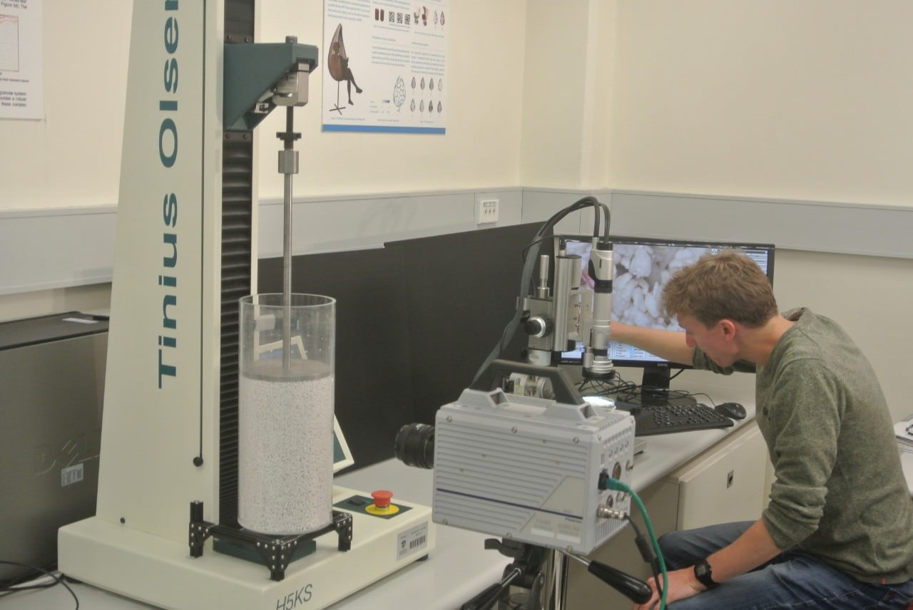 Researcher inspecting granular materials under microscope