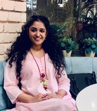 Picture of Neha Nagpal sitting on a chair, smiling 