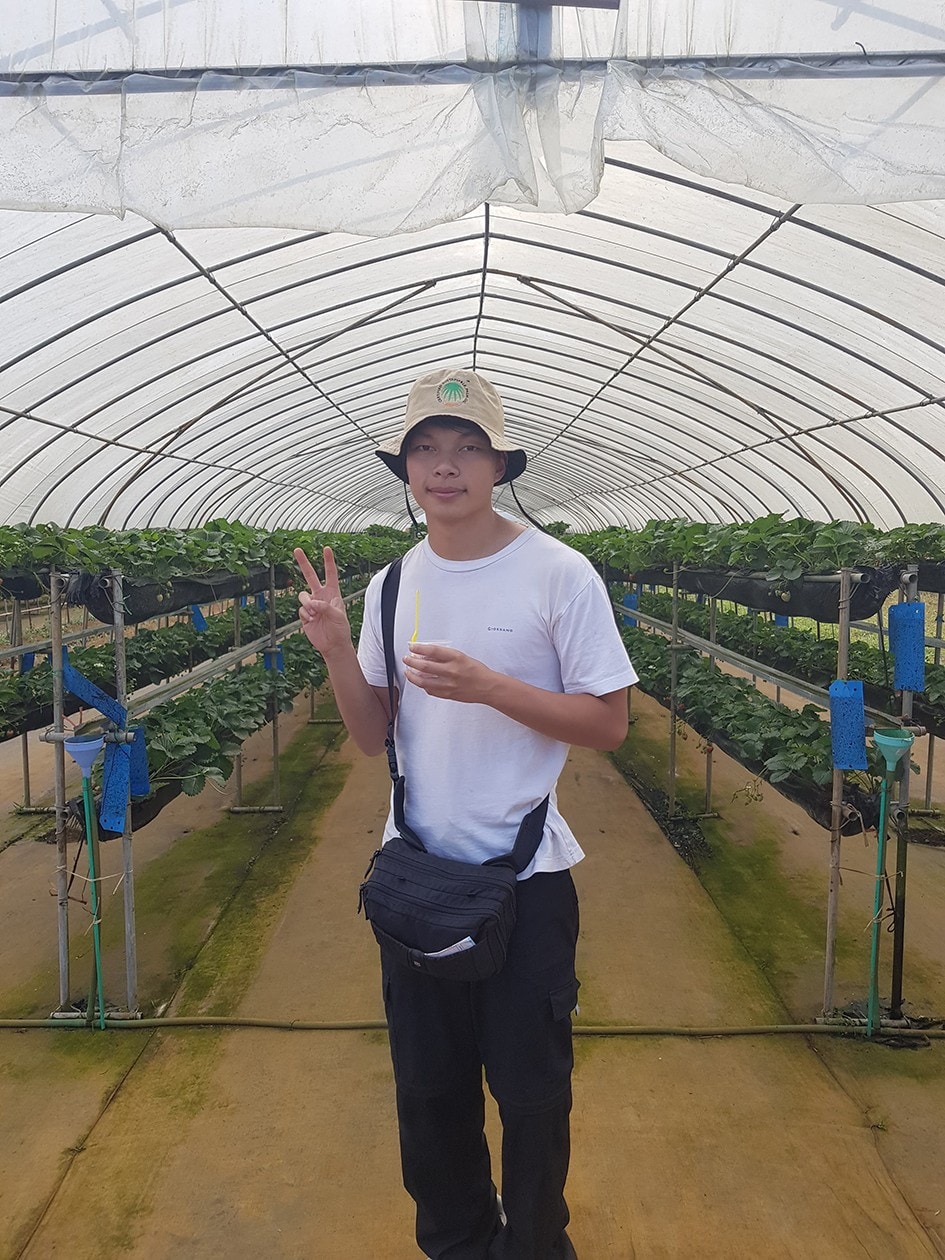 Student Oscar Wang inside a greenhouse