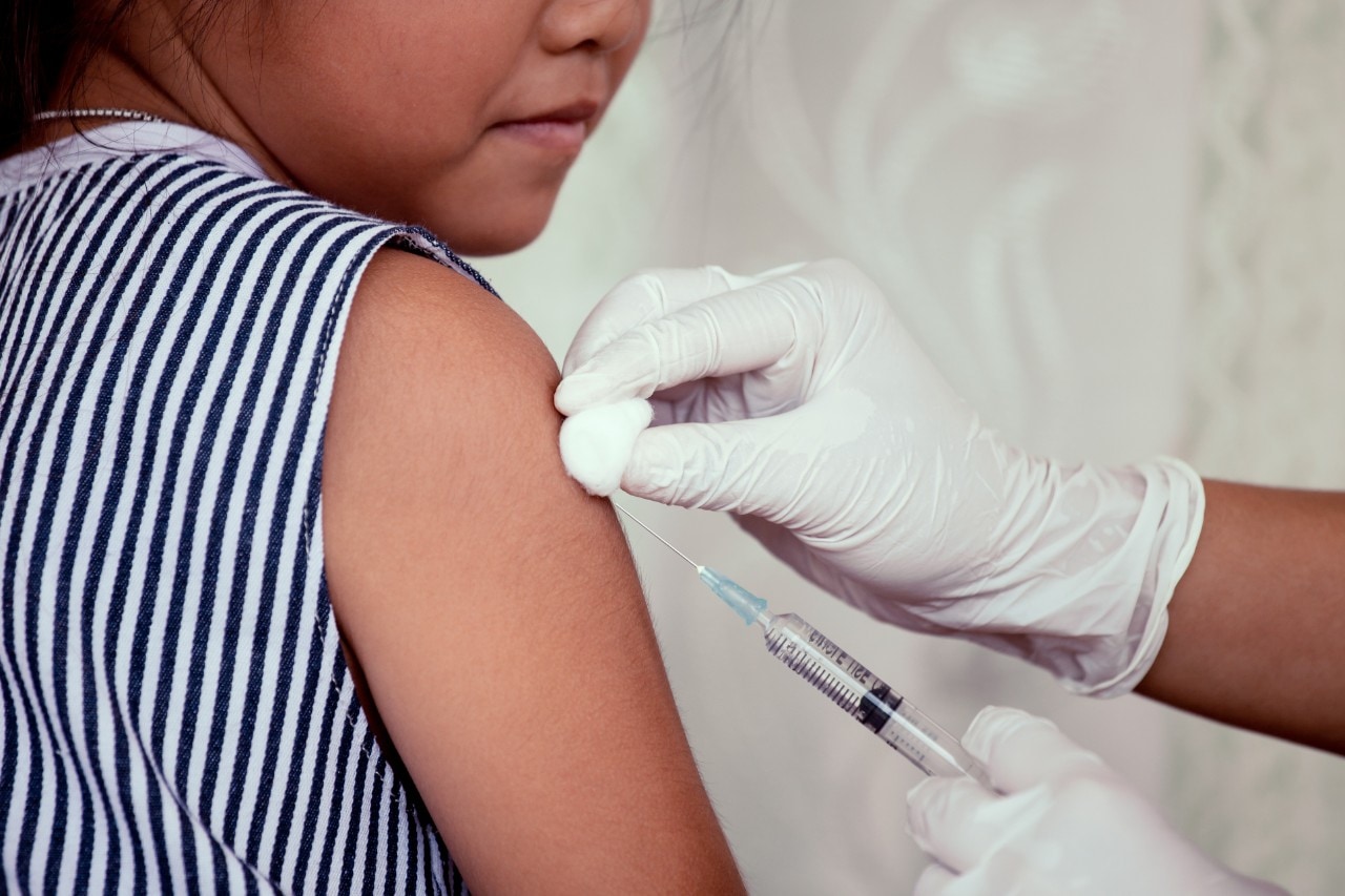 Doctor administering vaccination in the arm of a young girl.
