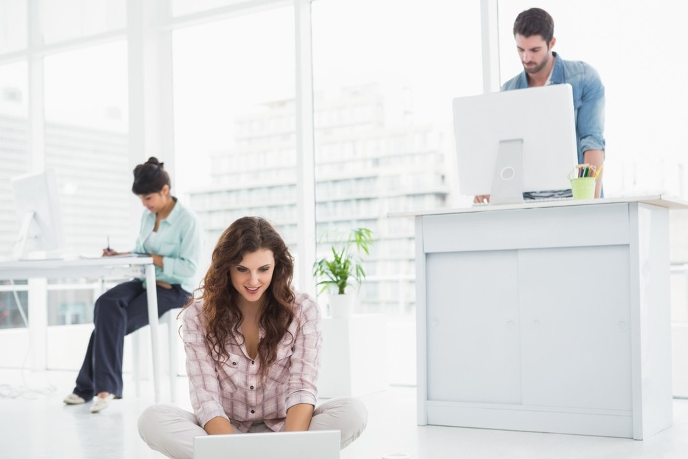 Workers in office using traditional and sit stand desks 