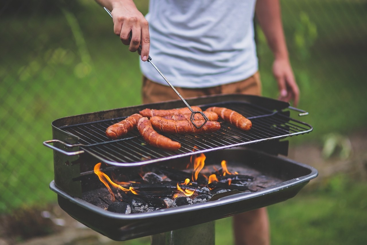 A man cooking sausages at a barbecue. 