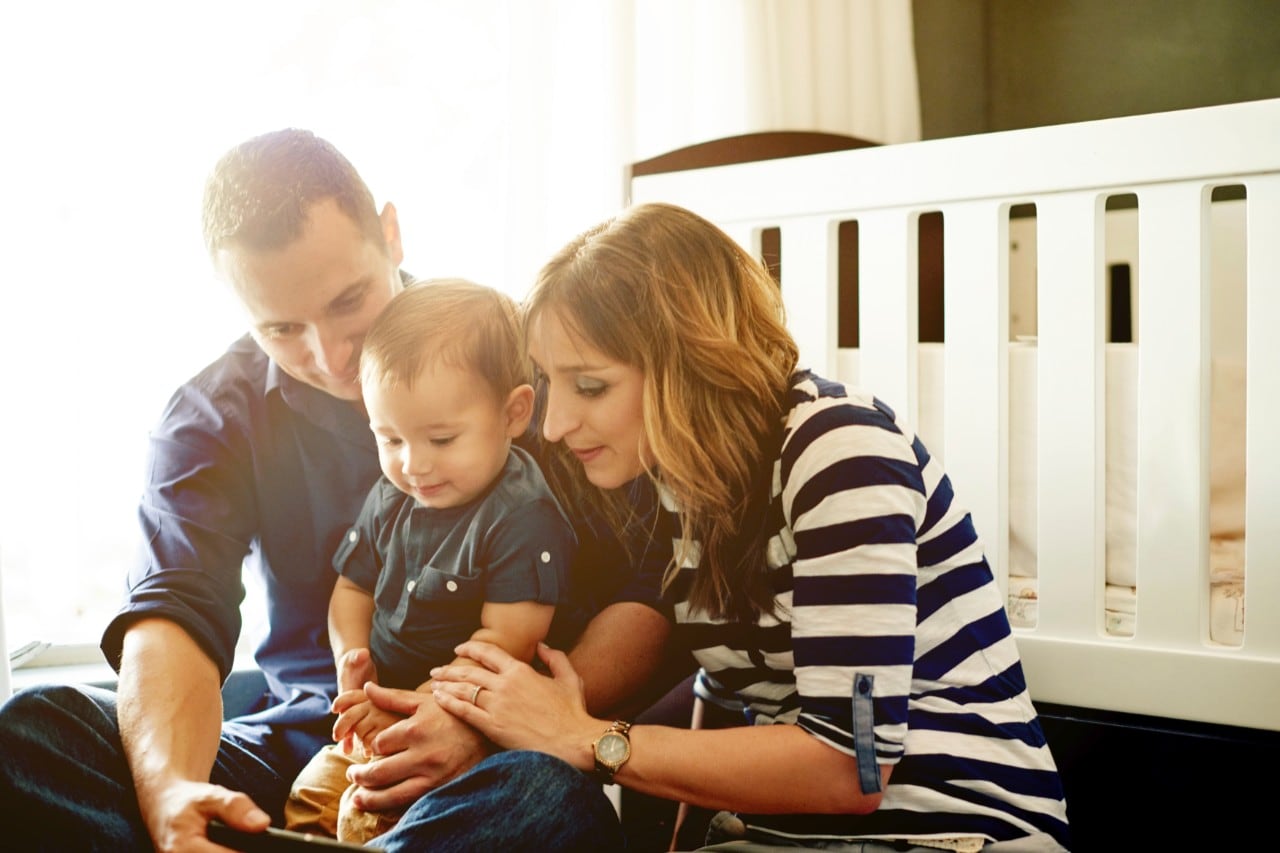 A young family watch a smartphone screen. Image: iStock 