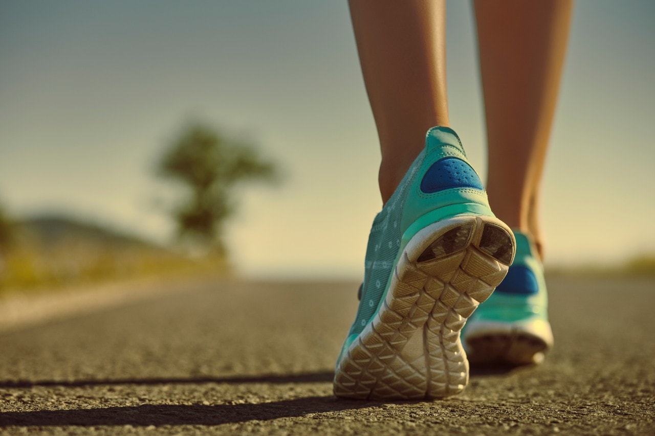 A woman's feet in blue running shoes on a road.
