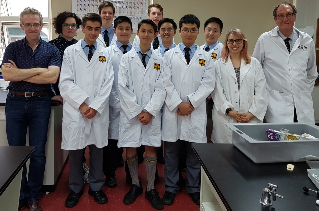 University researchers pictured with Sydney Grammar students, in lab coats, and their teachers
