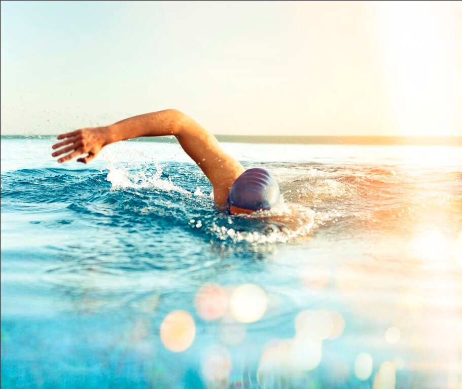 Swimmer in blue bathing cap doing freestyle in a pool.