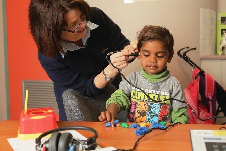 A photot of an audiometry nurse checking child's ears 