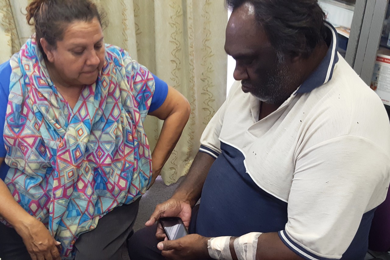 A photo of Aboriginal Health Education Officer Helen Ferguson and patient Ken Jackson using the iECG device.