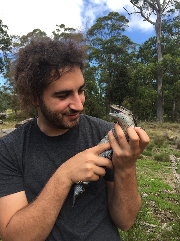 Joshua Kemsley with a blue-tongue lizard in the field