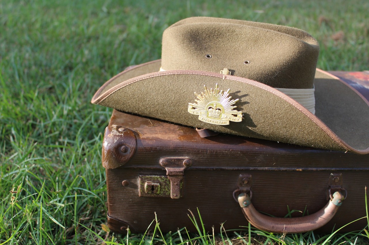 Army hat with ANZAC pin sitting atop a suitcase