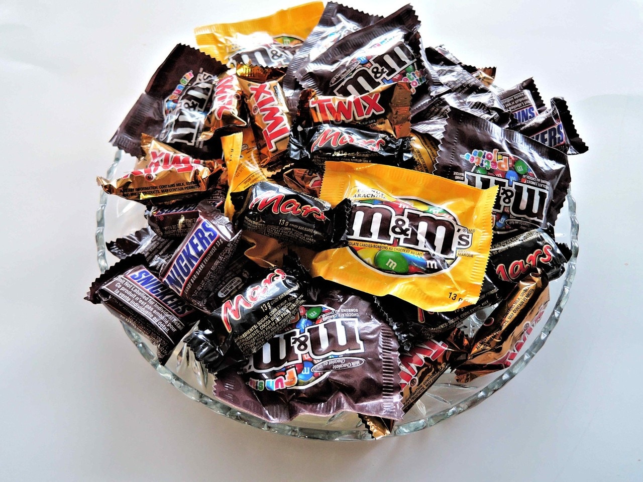 Bowl filled with fun size snickers, mars bars and packets of m&ms.