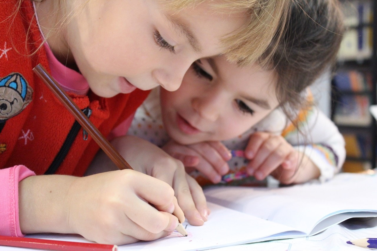 Two children writing in a notebook