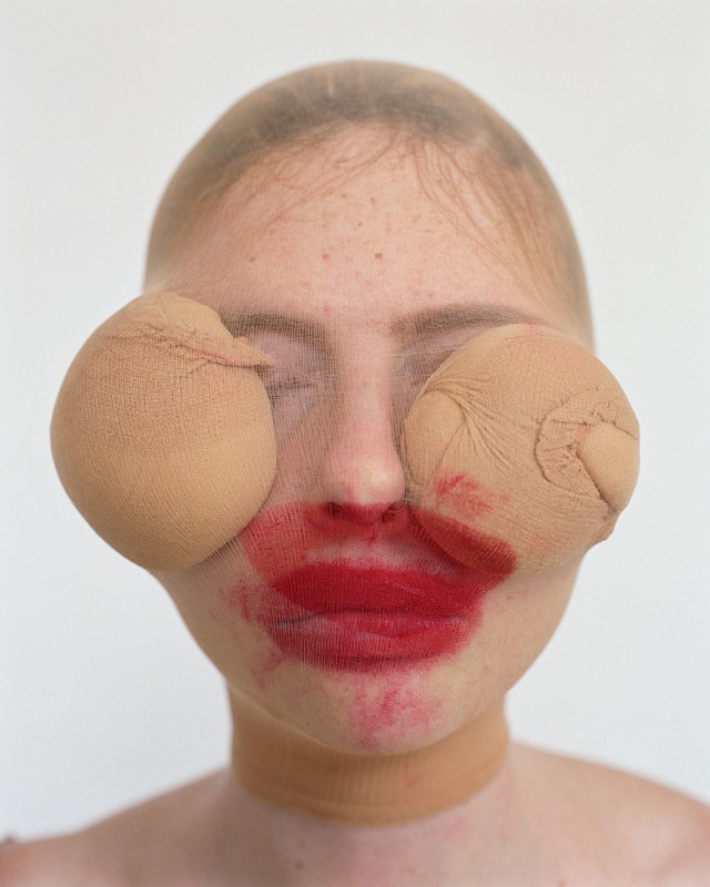 image of woman with face covered in lipstick and with pantyhose balls over eyes 
