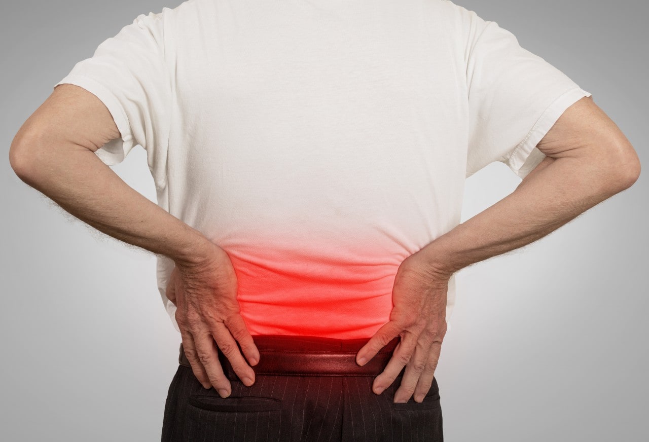 Photo of a man with back pain, his hands are on his lower back