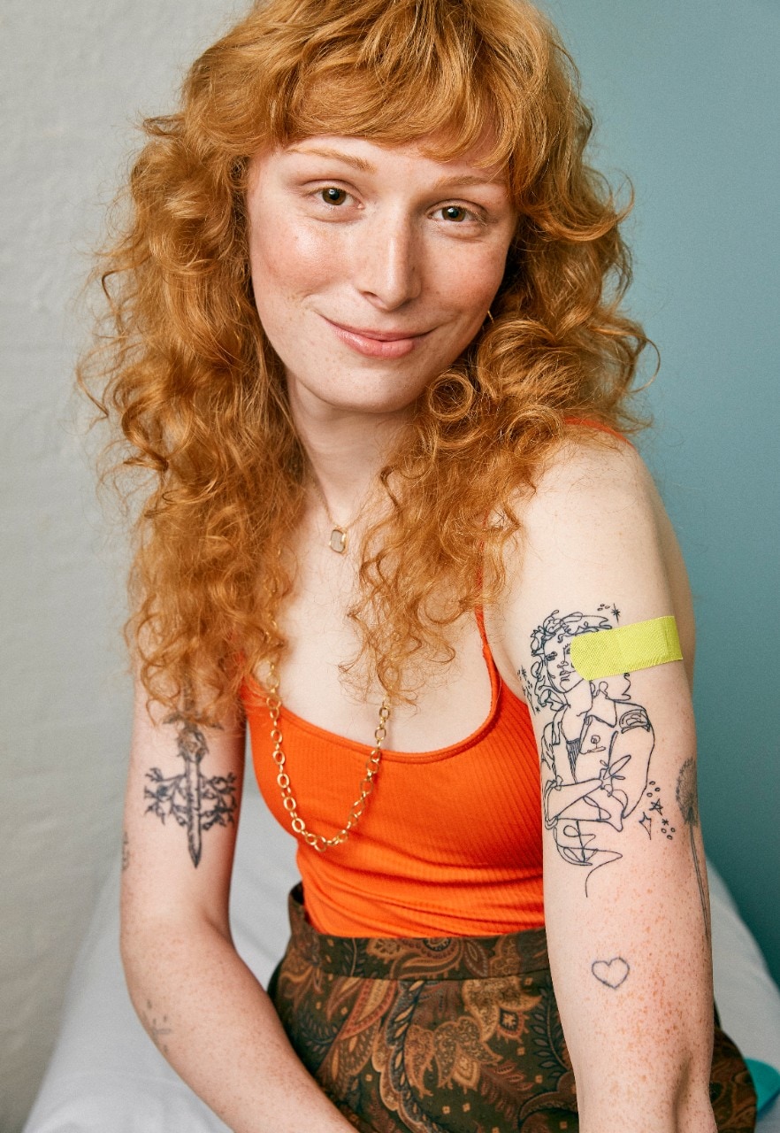 Photo of a young woman with a bandaid on her arm after getting the vaccine.