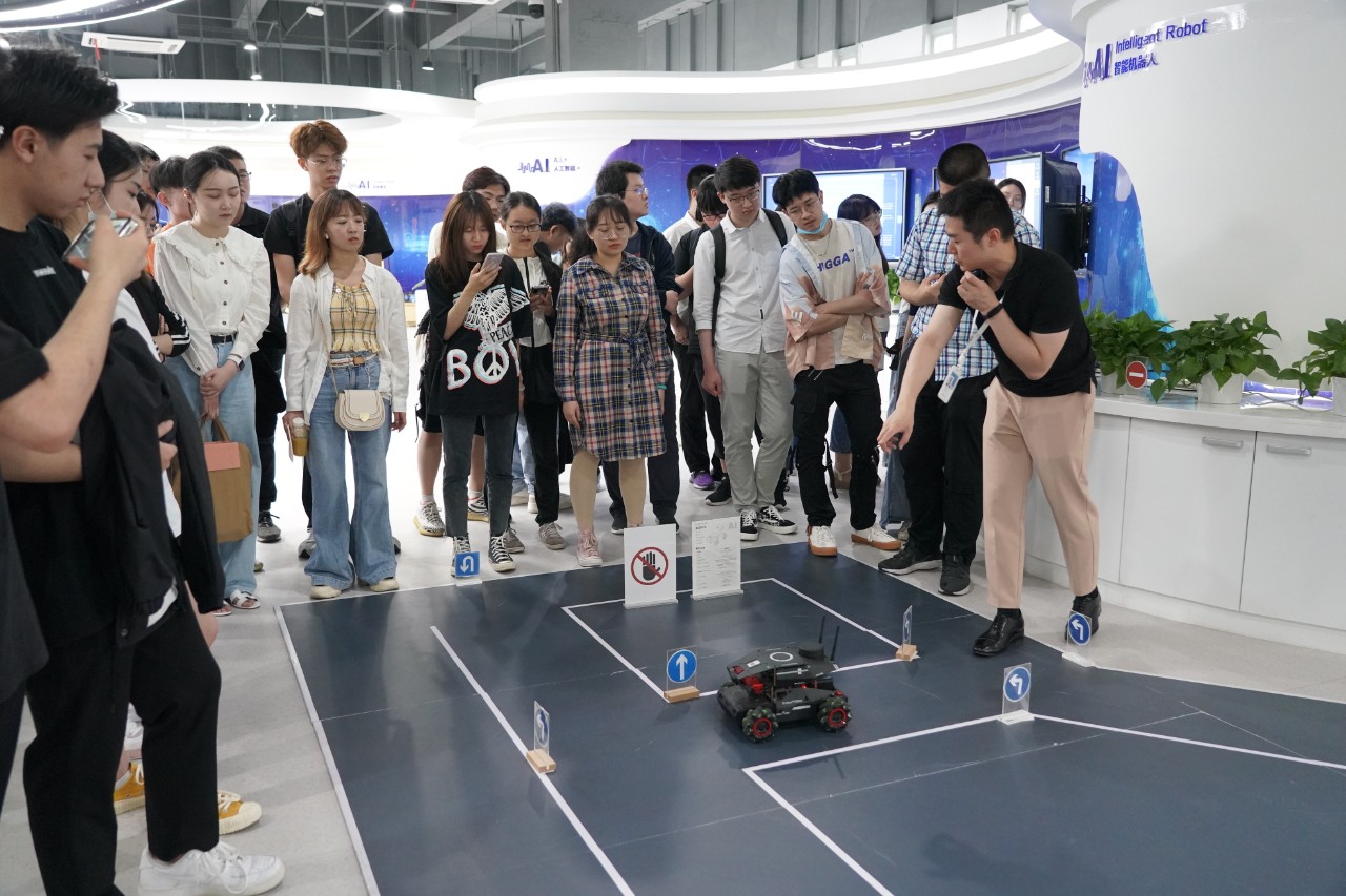 Students stand around a small robot with wheels