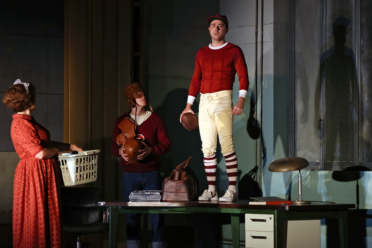 photo of an actor standing on a table pretending to be a football player with a ball
