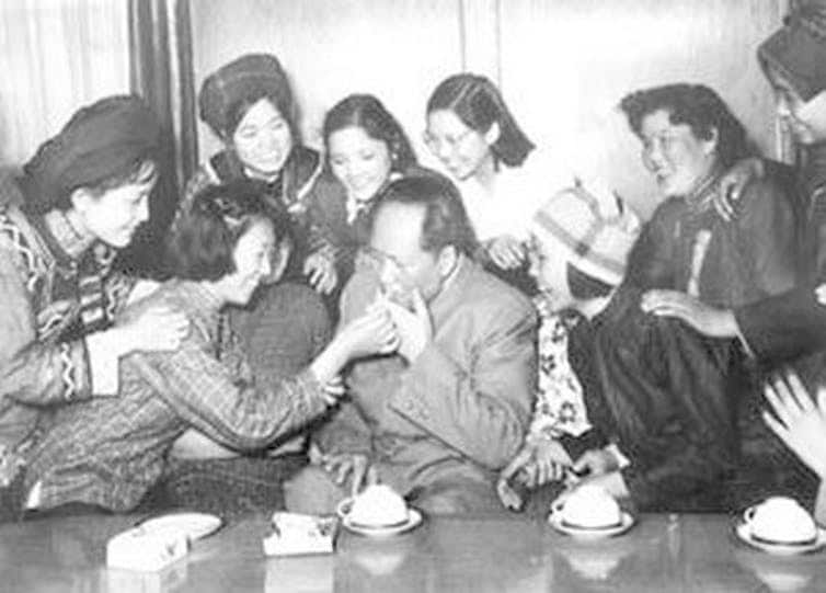 Black and white photo of Mao Zedong with female representatives of the Democracy Youth League of China at the 3rd National Representative Conference in 1957.
