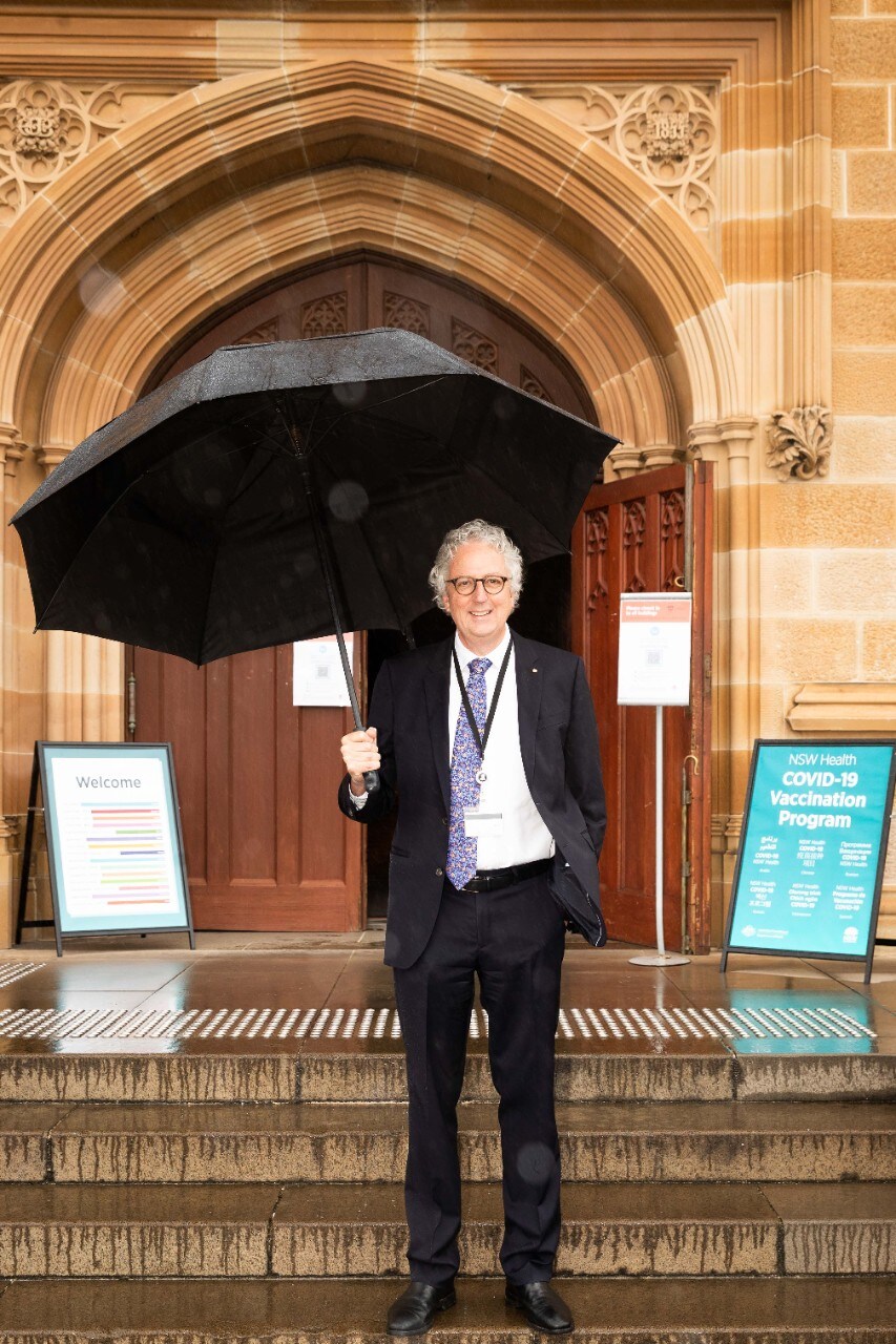Vice-Chancellor Professor Mark Scott outside the Quadrangle holding and umbrella