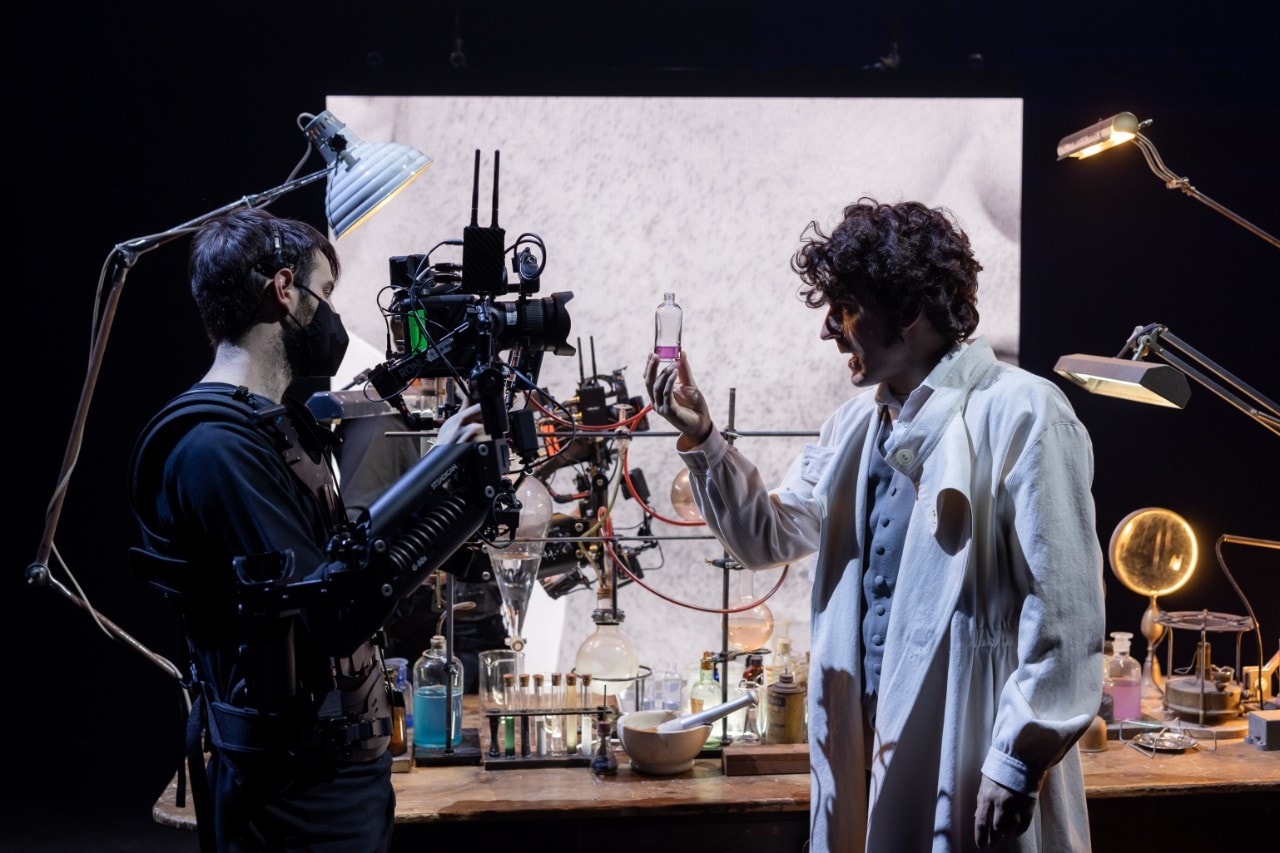 actor playing Dr Jekyll is in a laboratory and there is a camera filming him