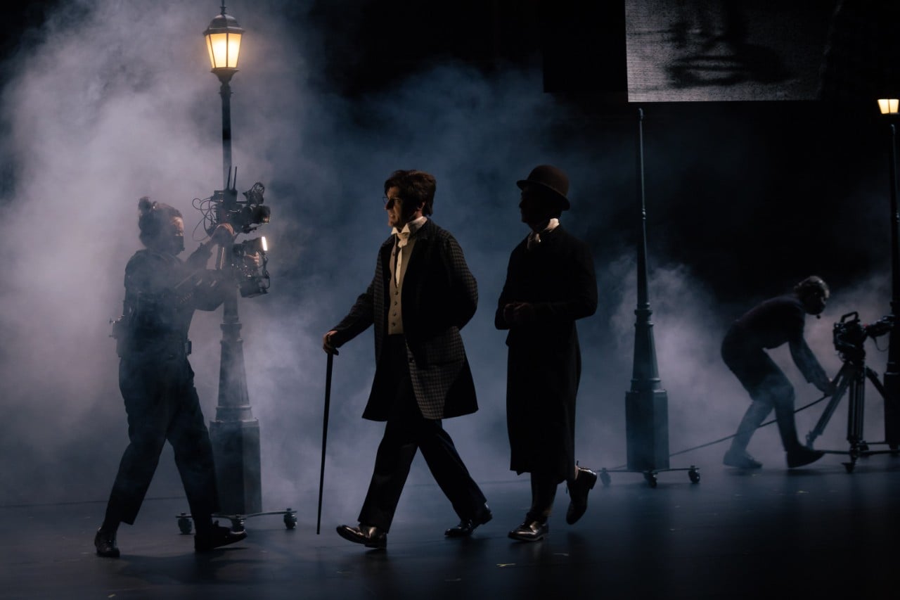 actors on stage in dark light with fog, it's a London street