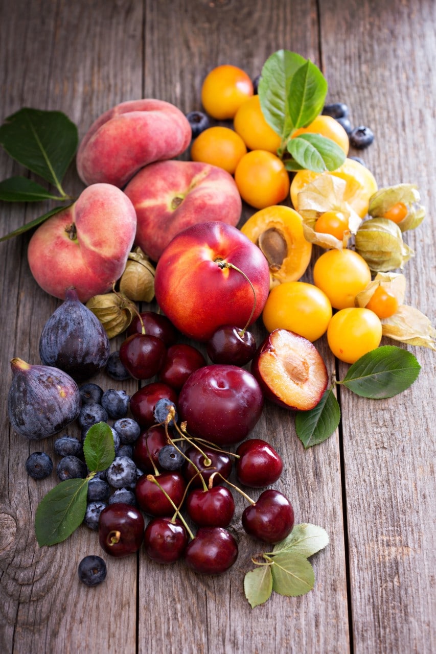 Fresh stone fruit including  on a table including cherries, plums, apricots and nectarines.