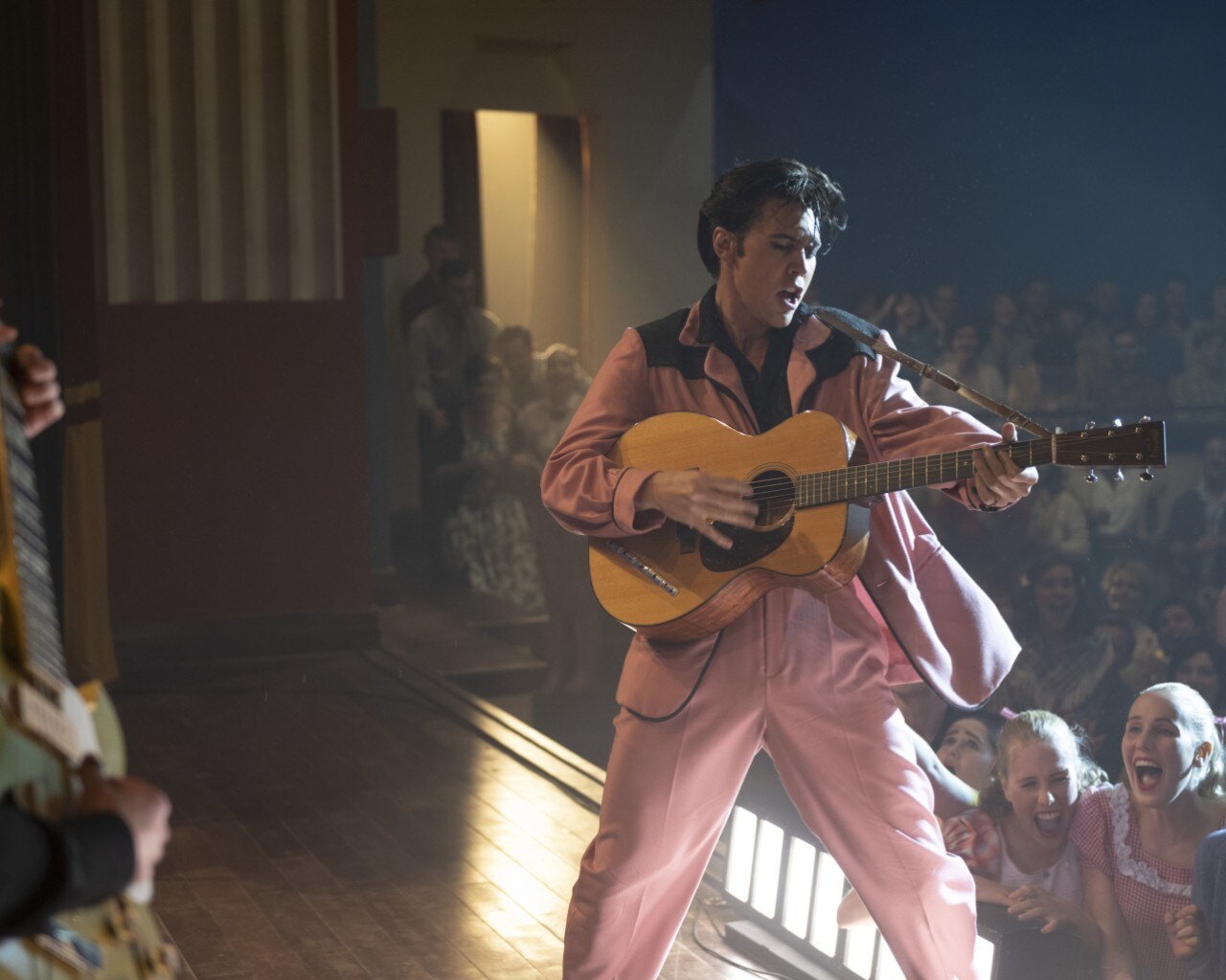 actor playing Elvis Presley dancing in a pink suit