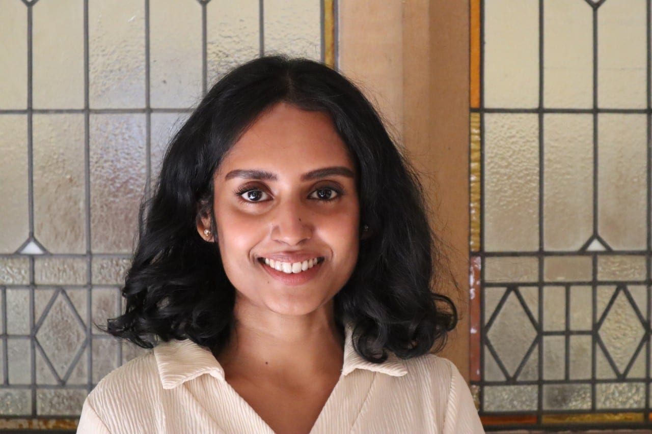Dr Niro Kandasamy is a young woman of Sri Lankan appearance wearing a white shirt and smiling at the camera