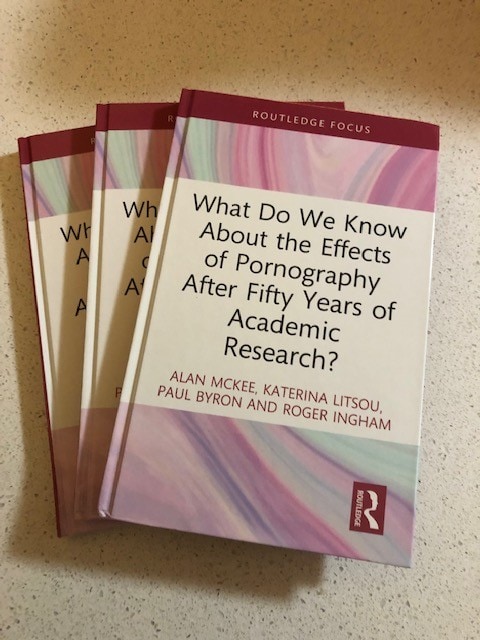 a stack of books with pink covers, the title is What do we know about the effects of pornography after 50 years of academic research?