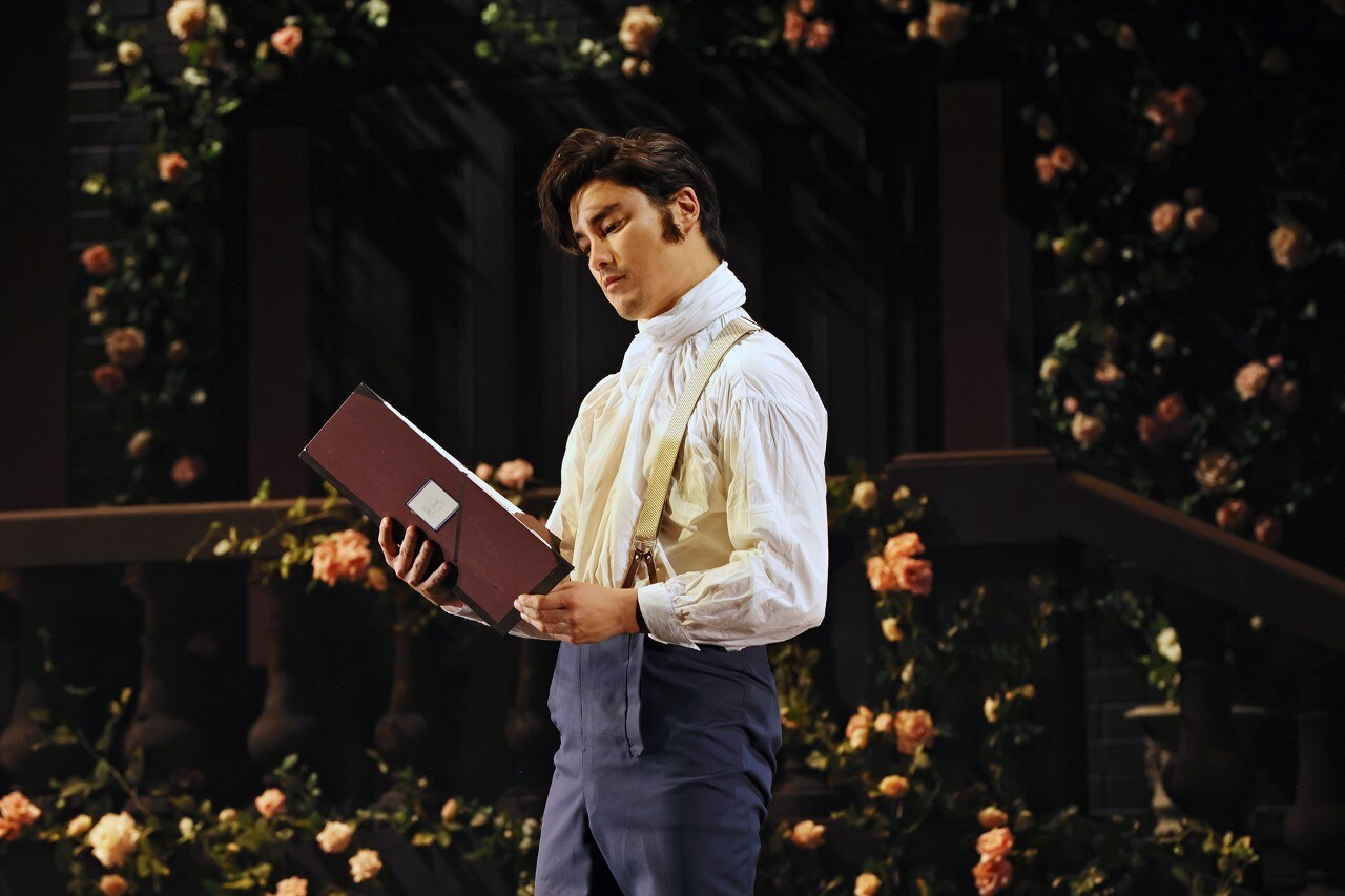 a young man in a fine suit reading a large book