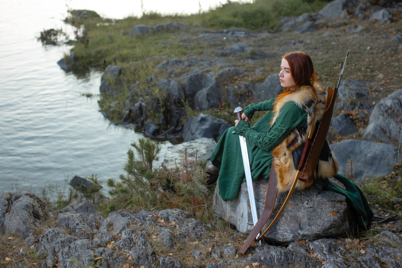 photo of a woman in a green Medieval style dress with a bow and arrow