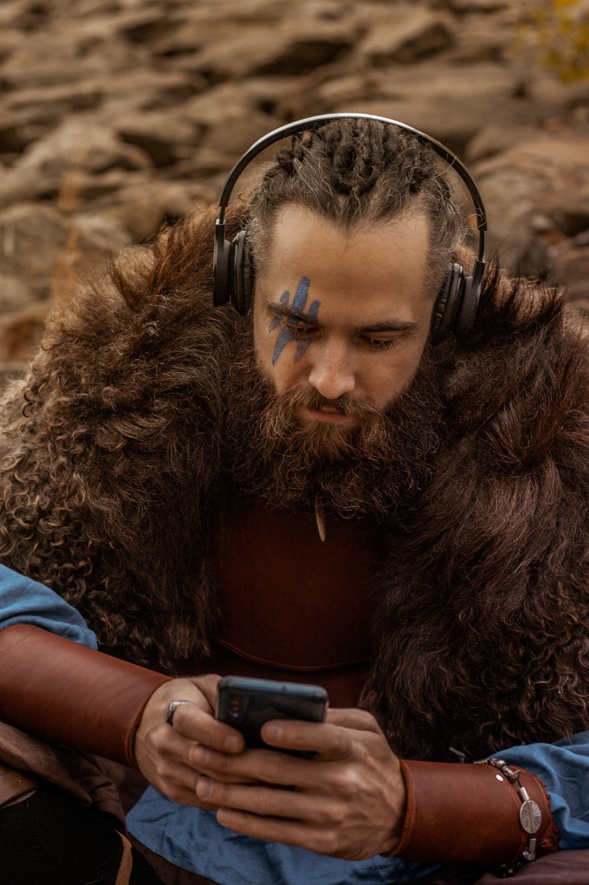 photo of a man dressed in warrior costume looking at his mobile phone