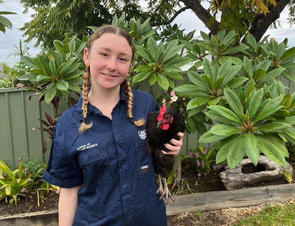 Brianna wearing a University of Sydney Vet School shirt holding a black chicken