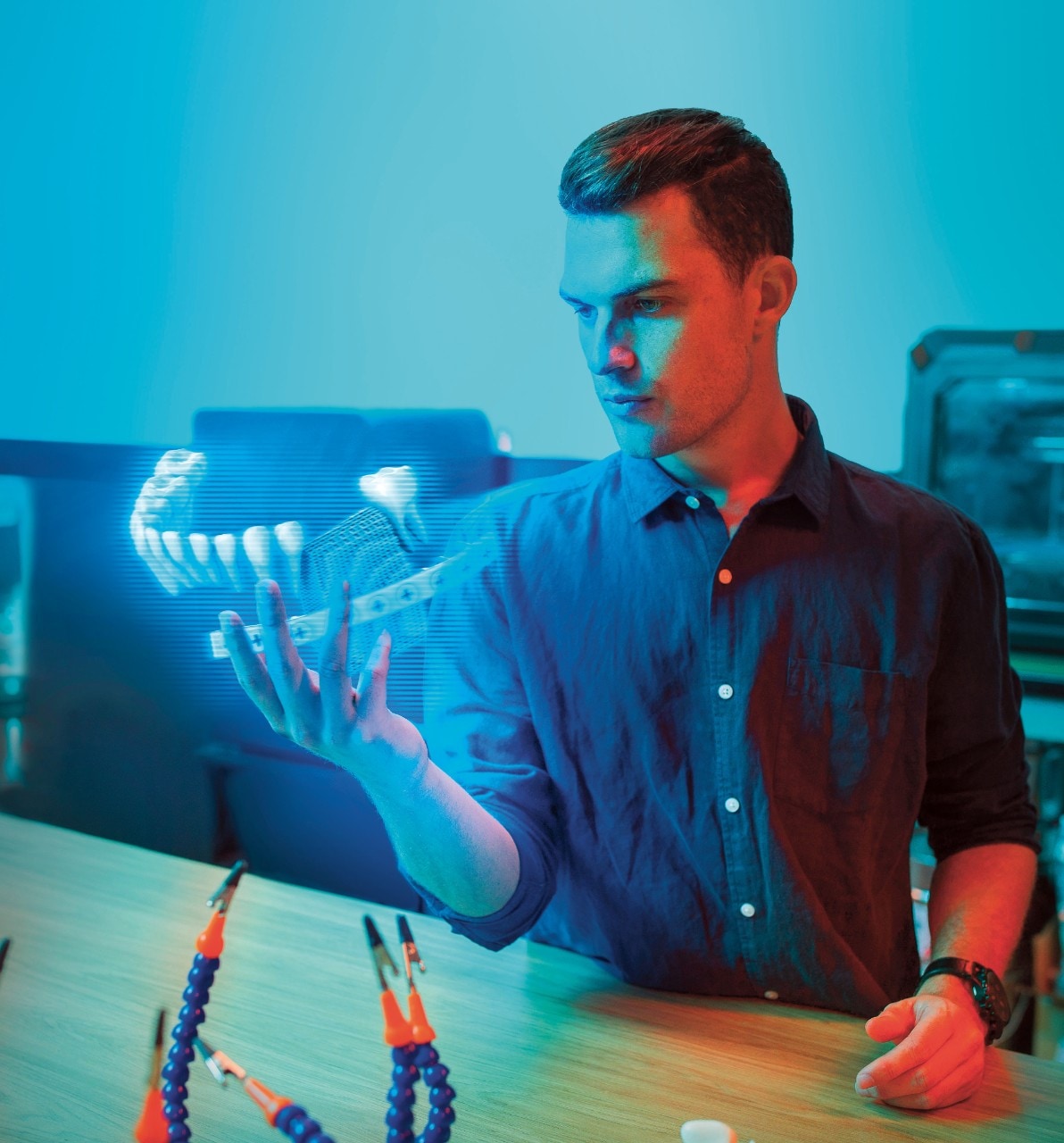 Ben Ferguson sitting at a desk with a holographic picture of a mouth elevating in his hand