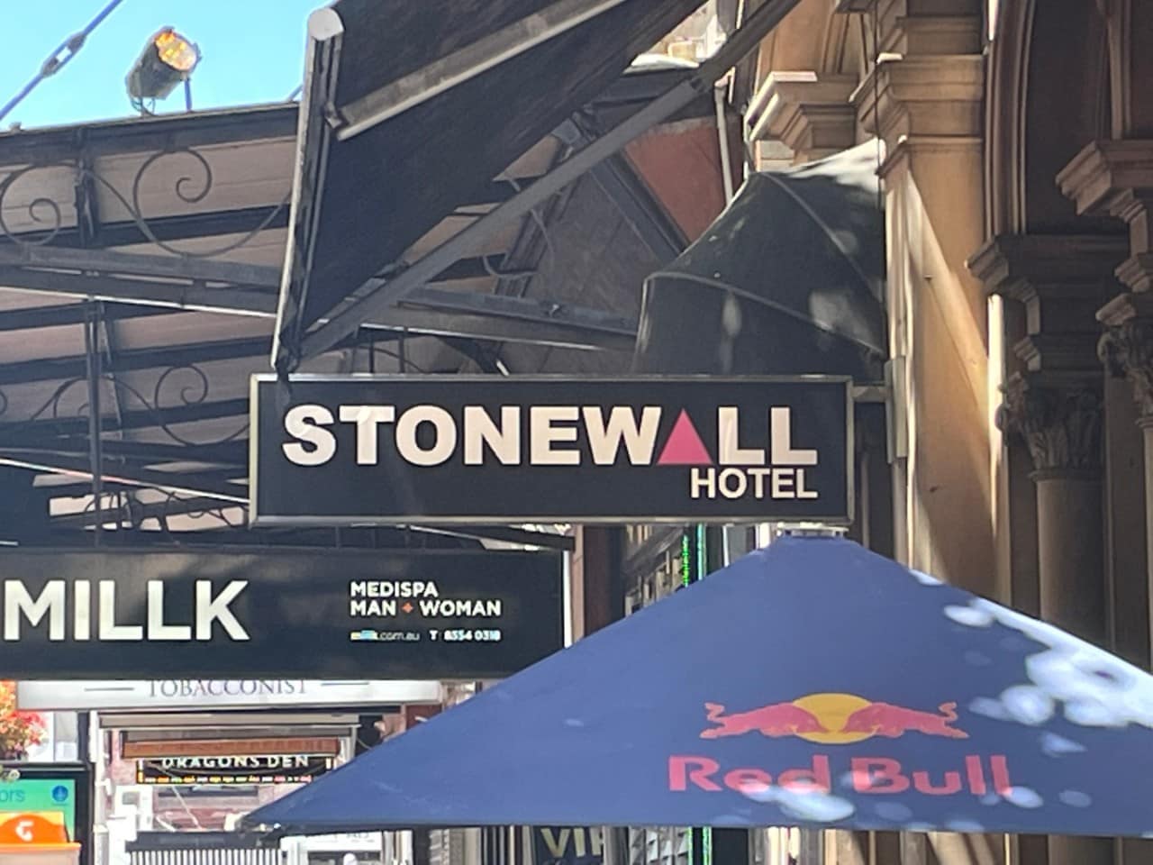 photo of a street sign that says Stonewall Hotel with a pink triangle for the a