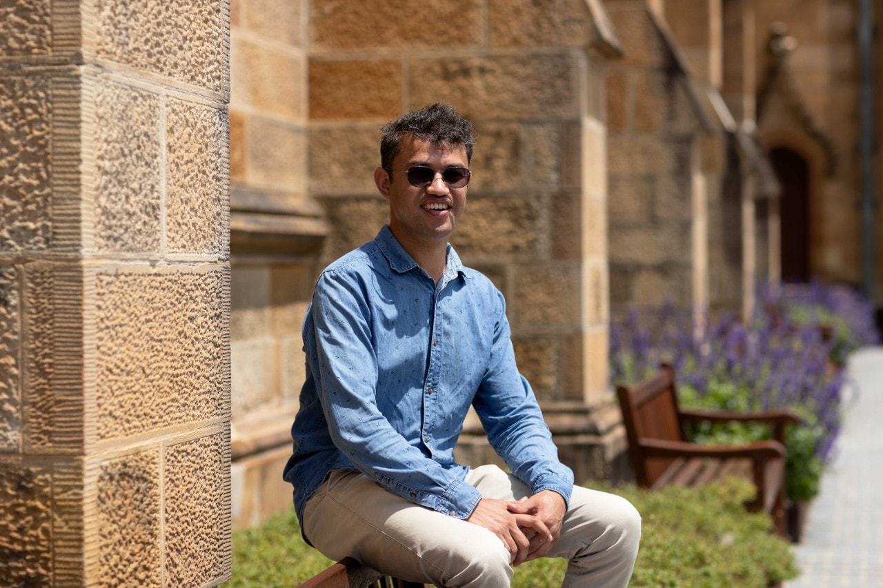Mohammad Reha sitting on a bench outside the Quadrangle