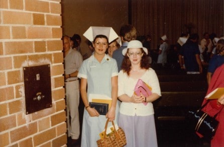 Lisa Jackson Pulver standing with a friend wearing her nurse's uniform - the uniform is an older style blue uniform and features a large hat.