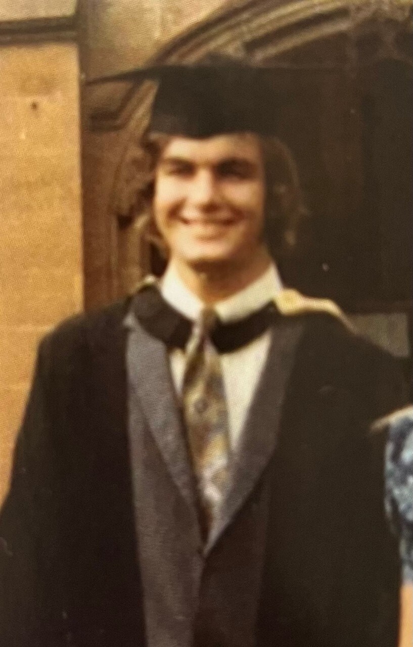 Old photo showing David Bell in graduation regalia smiling at the camera